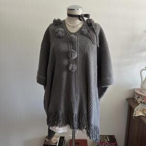 Gray knit poncho with fur pom poms